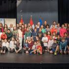 image of a large group of young students and some adults on a performance stage with flags in the background