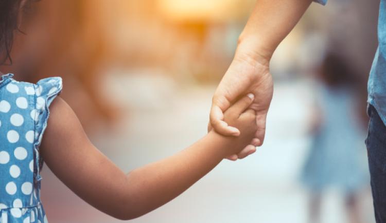 child and adult holding hands