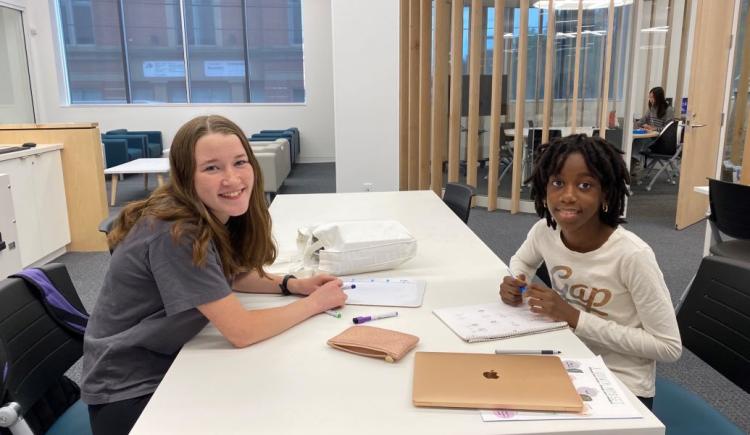 Tutor and young child sit together at a table